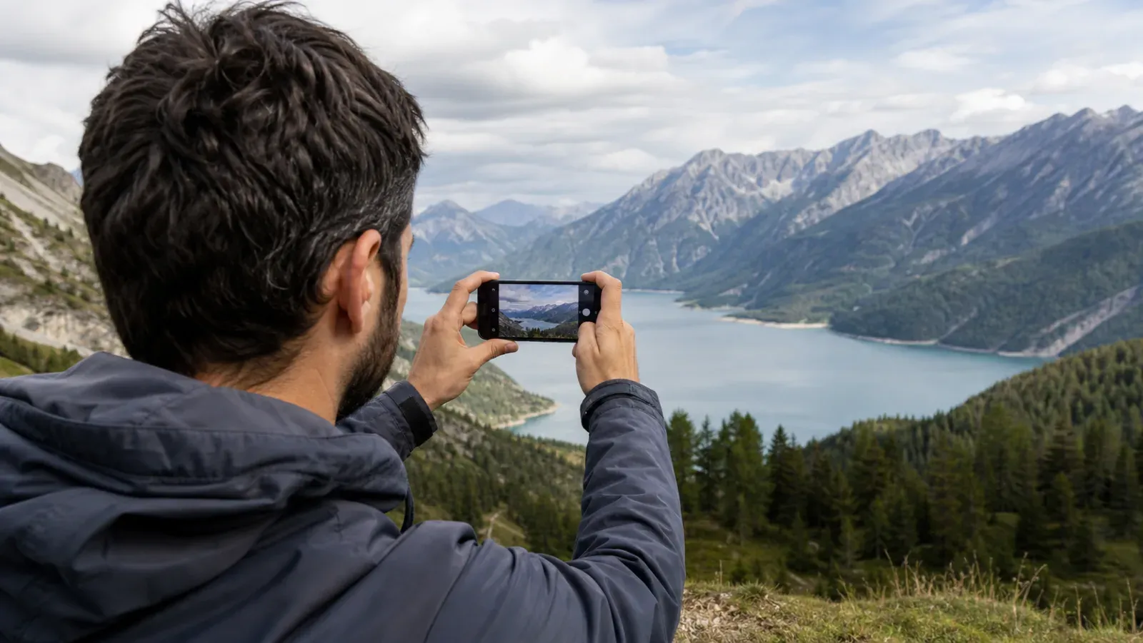 Путешественник фотографирует горное озеро на смартфон