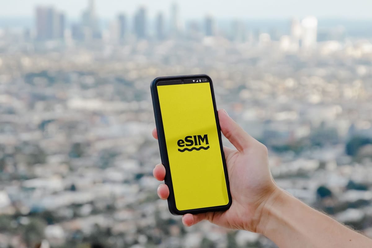 Смартфон с экраном eSIM в руке на фоне города